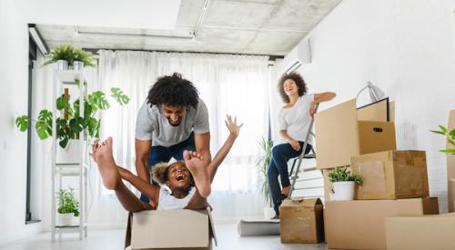 Family with young child moving cardboard boxes into new home 