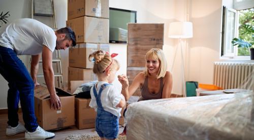 young family packing boxes in bedroom in preparation for moving house