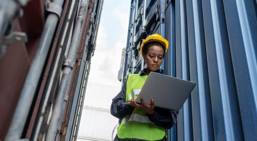 Women wearing construction gear and looking at laptop on job site