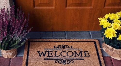 Welcome mat and flowers on house doorstep