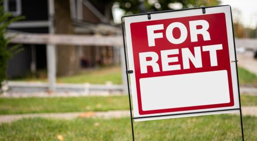 Red and white 'for rent' sign on residential lawn