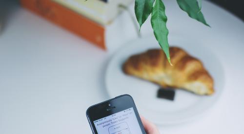 Person using mobile device with books on the table