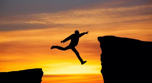 Man jumping between two cliffs