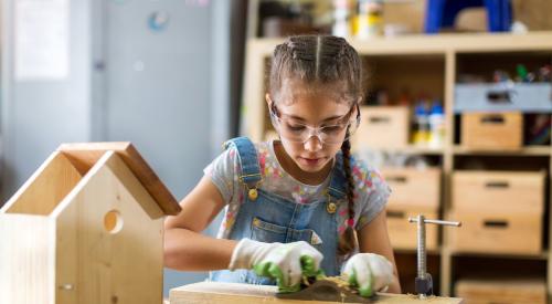 Young girl building birdhouse