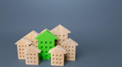 Small green wooden house surrounded by unpainted wood houses