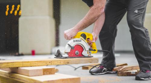 Man using hand saw to cut two by fours