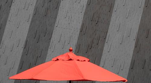 coral colored umbrella against grey backdrop