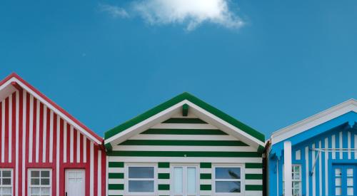 Three striped houses against a blue sky