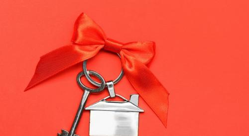 Silver house keys wrapped with red ribbon against red background