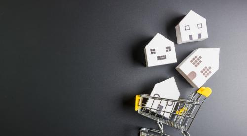 Small model homes in shopping cart with black background