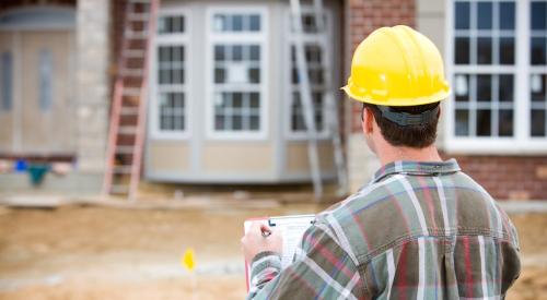 Home builder standing in front of house under construction