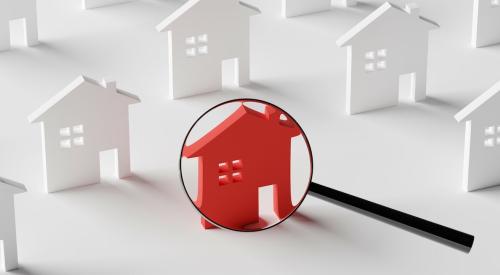 Magnifying glass over red house surrounded by white houses