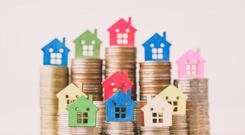 Colorful house models stacked on top of coins