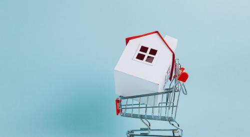 White house with red roof in shopping cart with blue background