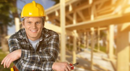 home builder leaning on tools in front of framing