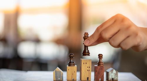 Model houses on chess board with players placed on top of pieces