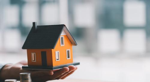 Small orange model home next to stack of coins