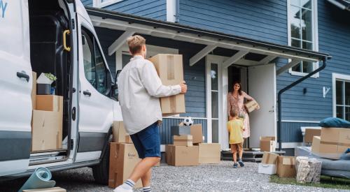 Homeowners unpacking boxes from van after moving into a new home