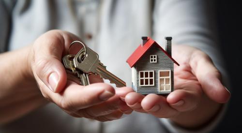 Hands holding house model and set of keys