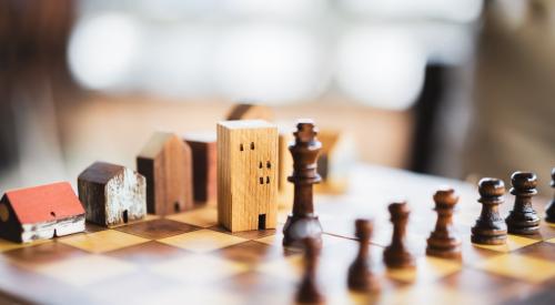 Small wooden houses lined up on a chess board