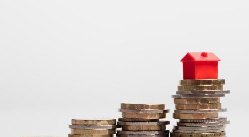 Red model home stacked on coins