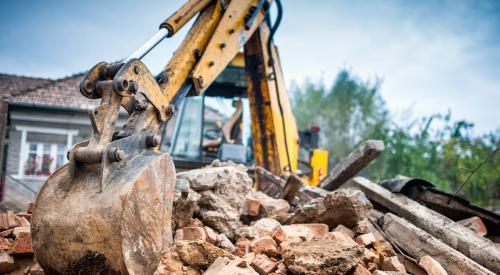 Crane digging in rubble from house demo