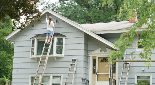 Person painting exterior of house