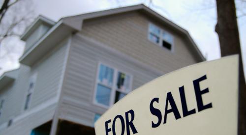 Beige house with for-sale sign in front