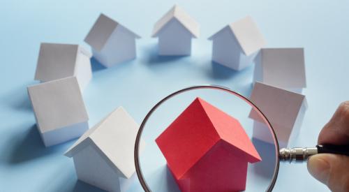 Circle of all white houses and one red house under magnifying glass