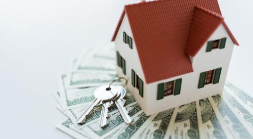 White house with red roof above stack of cash and house keys