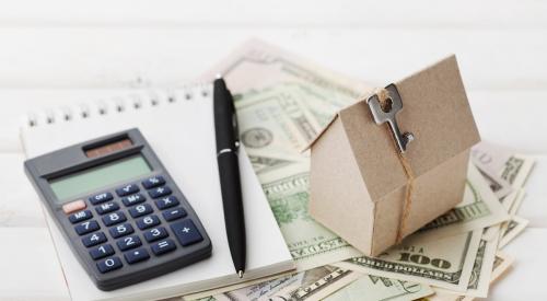 House, calculator, and notepad on stack of cash