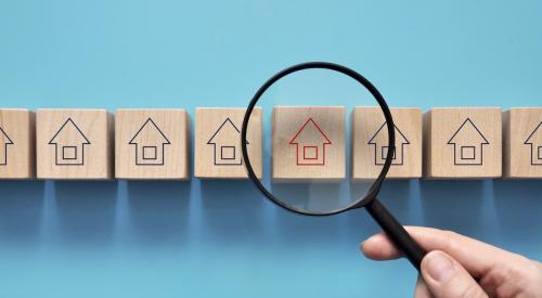 Magnifying glass over wooden block market with house outline