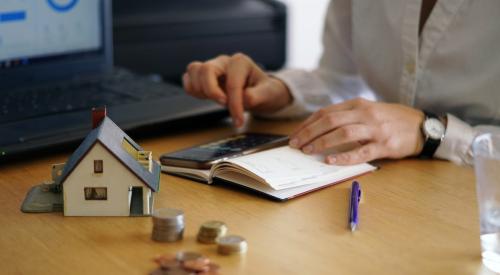 Person at a table calculating the cost to buy a new home