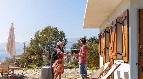 Homeowner greeting guest with suitcase outside of vacation rental 