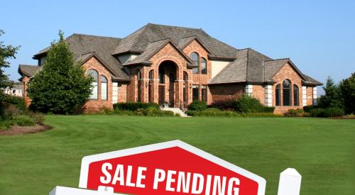 Red and white sale pending sign outside of large residential home