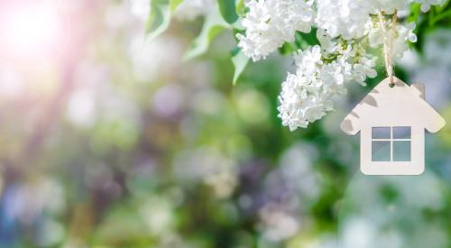 White home ornament hanging from tree with spring flower blossoms