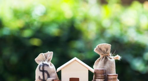 Small wooden house next to bags of coins