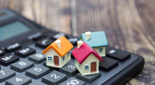 Small, colorful house models on top of calculator