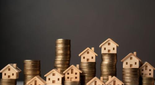 Small wooden houses on stacks of coins