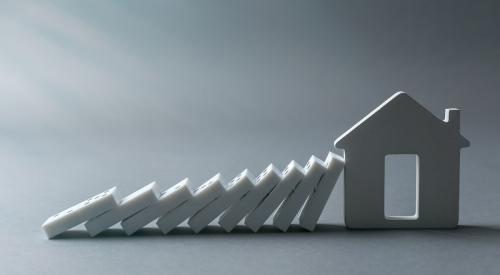 Dominoes falling onto white house with gray background