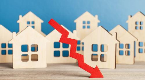 Wooden house models behind a red downward arrow