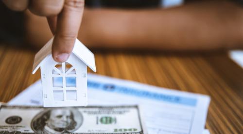 White model house on stack of money above bank paperwork