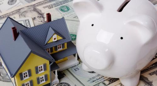 House model and white piggy bank on stack of cash