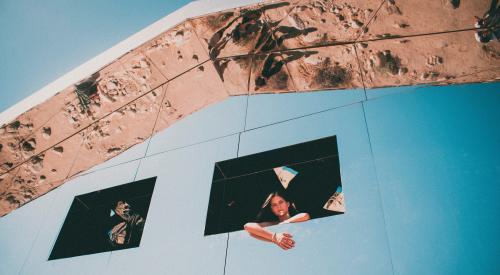 Millennial woman looking out of window of structure in Palm Springs, Calif.