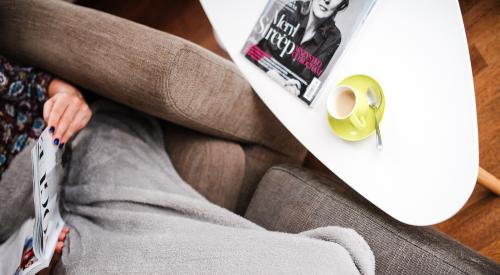 Woman on sofa with cup of tea and magazine on side table