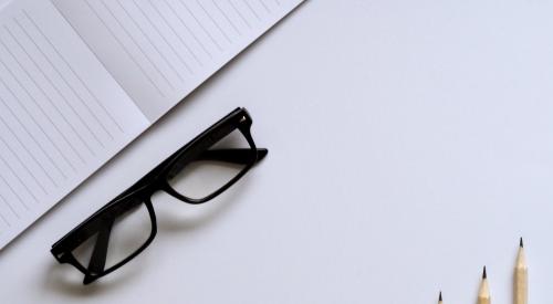 Glasses, paper, pencils on a desk