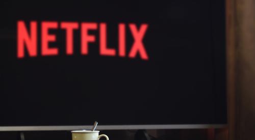 TV with Netflix title screen on, with mug on tabletop