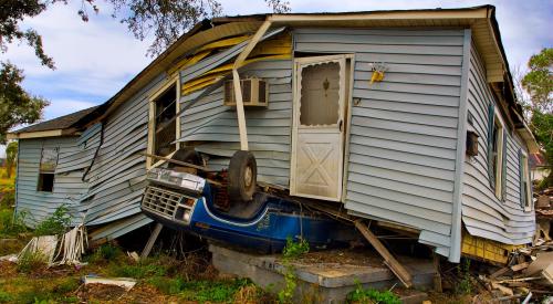 House that has sustained severe tornado damage, with car stuck under foundation