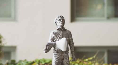 Miniature toy person with megaphone outside of building exterior