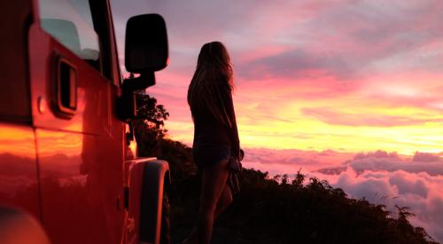 Person looking over land at sunset with Jeep Wrangler